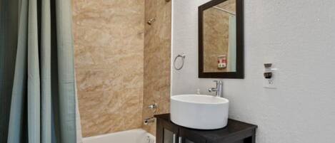 Une salle de bain avec une baignoire, un lavabo et un miroir au mur.