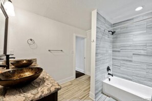 Une salle de bain avec un comptoir en marbre, un grand miroir et une douche aux carreaux gris.