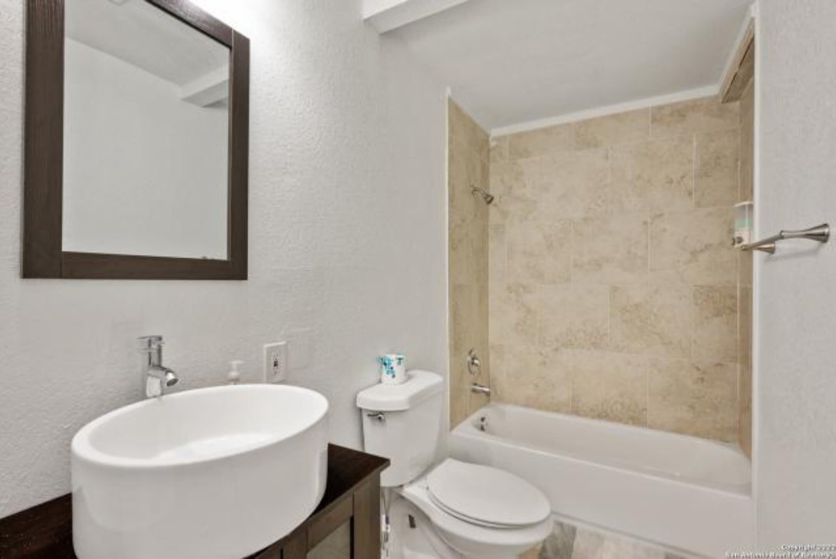 Un baño con lavamanos, inodoro y bañera blancos.