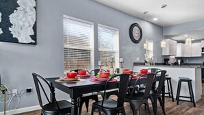 Un espace de salle à manger moderne avec une table noire dressée pour six personnes, entourée de chaises noires.