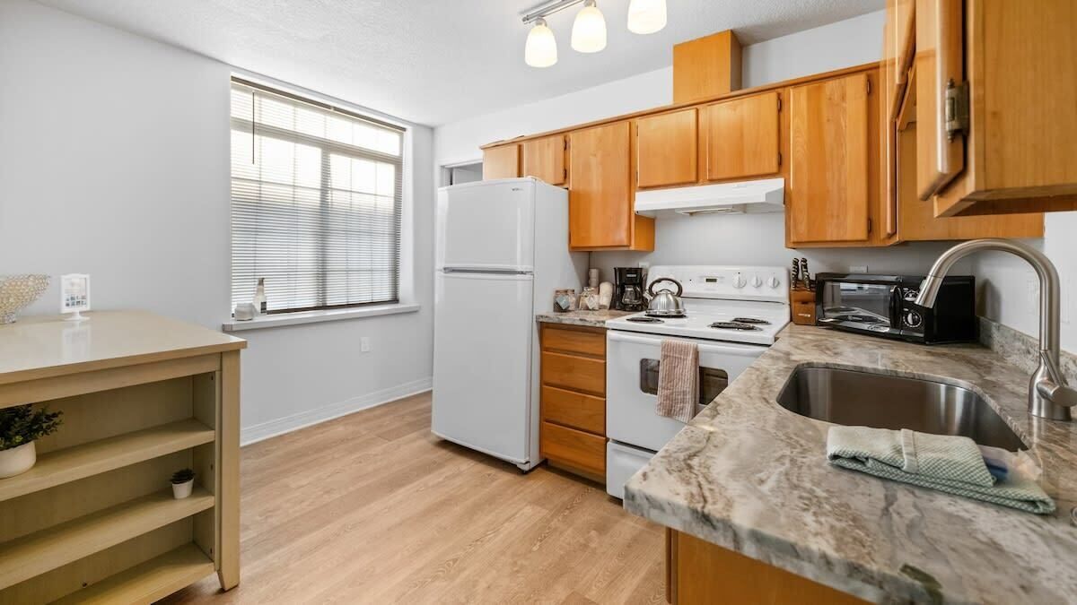 Una cocina moderna con armarios de madera, un refrigerador blanco, una estufa y un lavamanos.