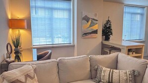 A living room with a beige sofa, a lamp, a small Christmas tree, and a painting on the wall. - #StayInMyDistrict Downtown Loft2 (Vancouver)