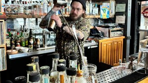 A bartender mixing drinks in a bar with shelves of liquor bottles and a counter with various bar tools. - #StayInMyDistrict Downtown Loft2 (Vancouver)