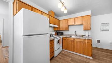 Una cocina con armarios de madera, un refrigerador blanco, una estufa y un microondas.