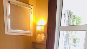 Une chambre d’hôtel avec un lit, une lampe de chevet, une fenêtre avec des rideaux et une vue sur l’extérieur.