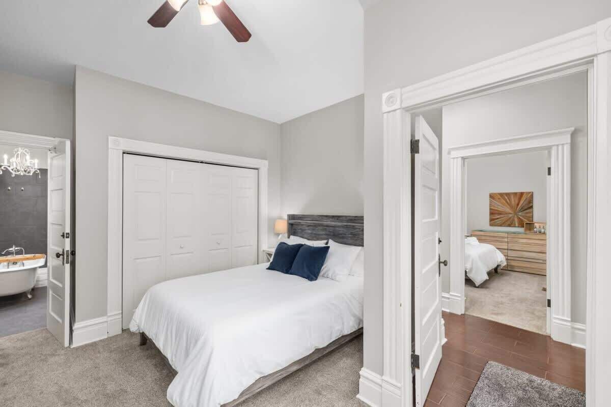 A bedroom with a bed, a nightstand, a dresser, and a bathroom with a bathtub.