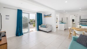 Un appartement moderne comprenant un salon, un coin repas, une cuisine et un balcon agrémenté de rideaux bleus.
