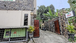 A gated entrance to a property named 'Kimara Home Stay' with a stone facade and a sign indicating 'Auto & Servicing'. - Kimara Homestay (Senggigi)