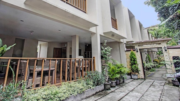 A multi-story building with a covered outdoor seating area and a gated entrance. - Kimara Homestay (Senggigi)