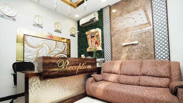 A reception area with a wooden desk, a plush sofa, clocks on the wall, and an air conditioning unit. - Taj Palace (Mumbai)