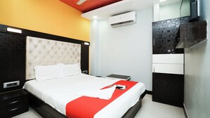 A modern hotel room with a tufted headboard, a red accent on the bed, a ceiling fan, an air conditioning unit, and a small bedside table. - Taj Palace (Mumbai)