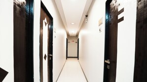 A narrow, well-lit hallway with doors on both sides leading to rooms. - Taj Palace (Mumbai)