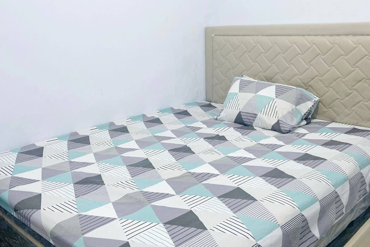 Una cama con una colcha de estampado geométrico y una sola almohada.