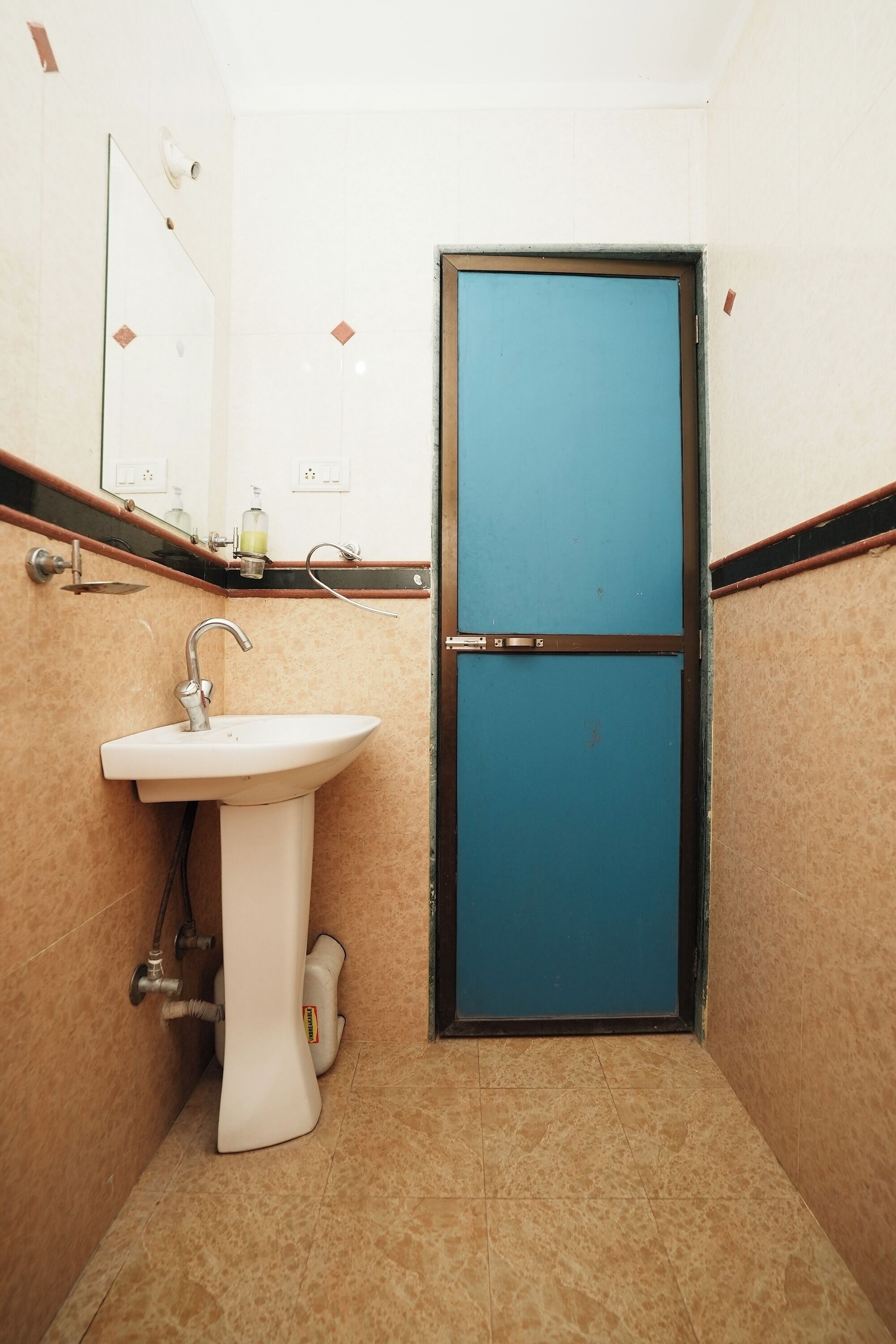 A small bathroom with a white sink, a mirror, and a blue door.