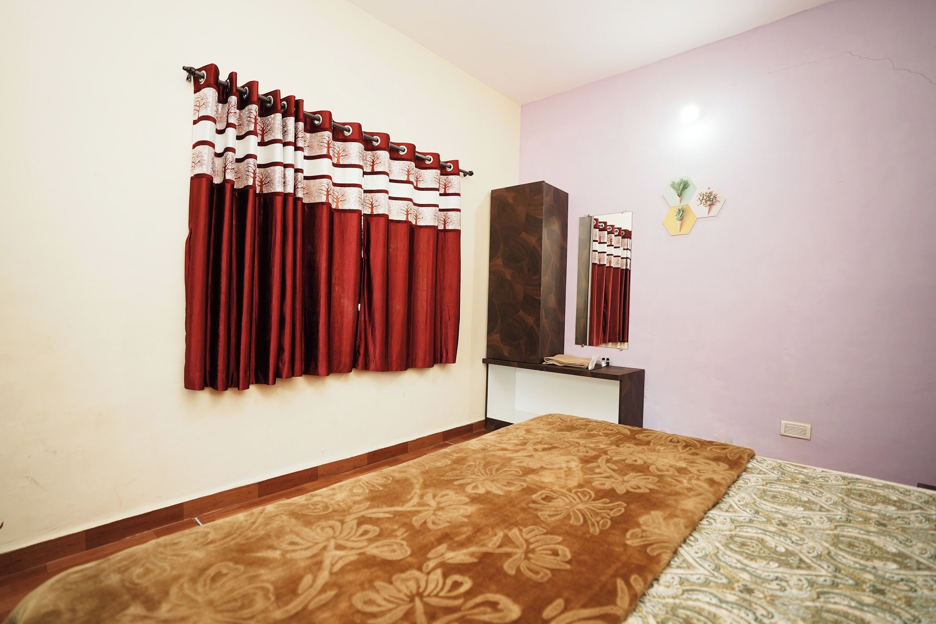 A bedroom with a bed, a nightstand, a mirror, and curtains.