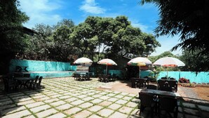 An outdoor patio area with tiled flooring and multiple tables and chairs. - Springfield Family Apartment (Mahabaleshwar)