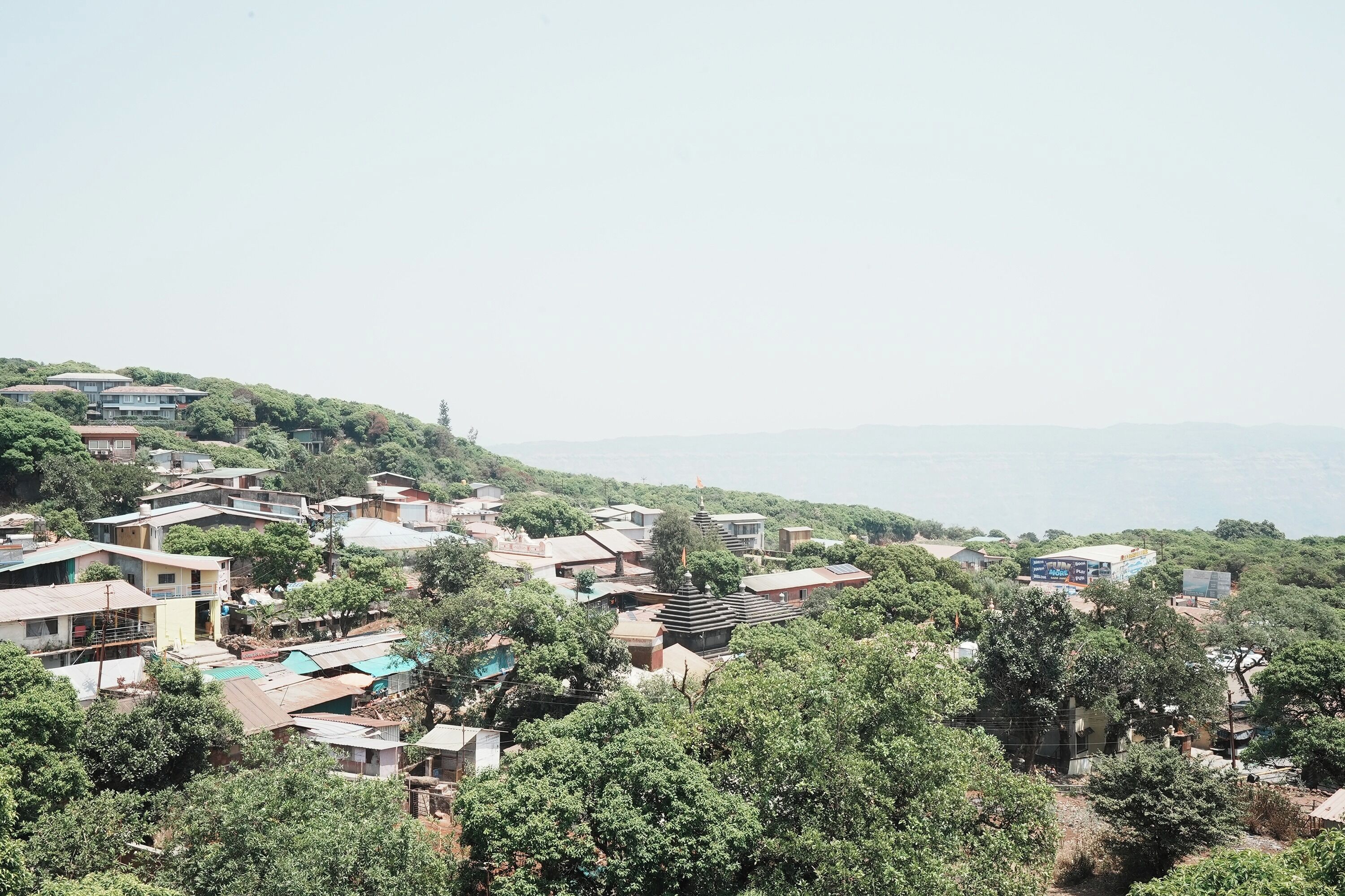 A residential area with houses on a hillside, surrounded by trees.