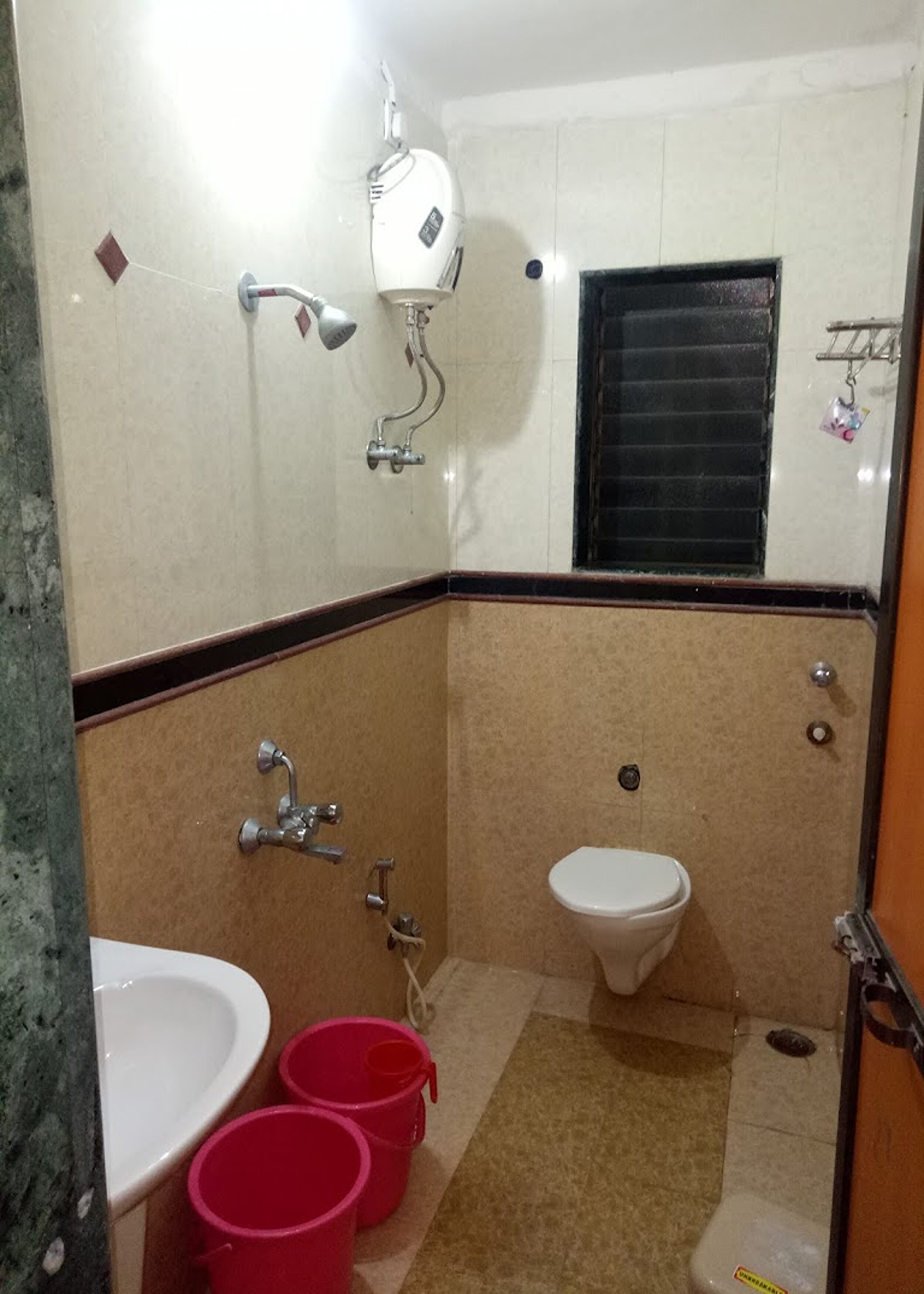 A bathroom with a toilet, sink, and shower. There are two red buckets on the floor.
