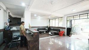 A reception area with a counter, seating, and a staircase. - Springfield Family Apartment (Mahabaleshwar)