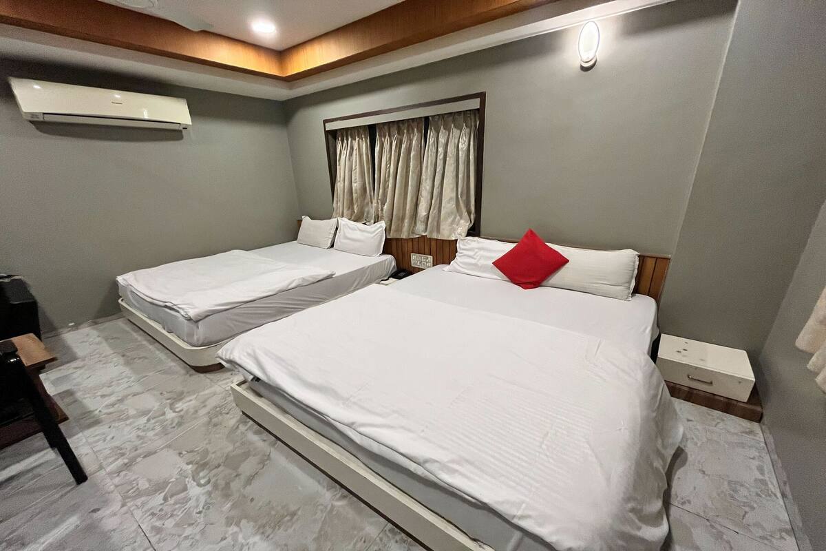 A hotel room with two beds, a wooden ceiling, an air conditioning unit, and a nightstand with a drawer.
