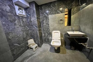 A bathroom with a toilet, sink, and a small step stool. - Hotel Om Balaji (Ahmedabad)