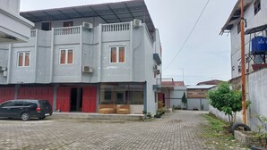 Un edificio de dos pisos con puerta roja y un balcón.