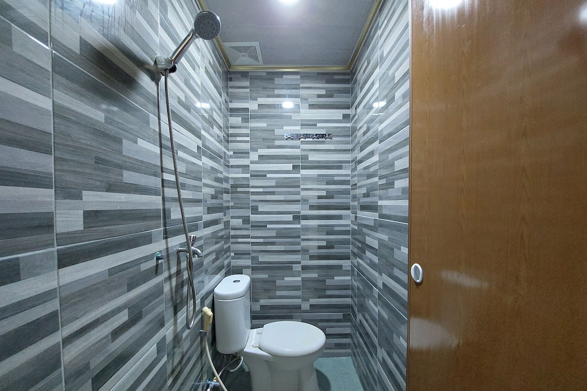 Une petite salle de bain moderne équipée d’un WC, d’une douche et d’un porte-rouleau de papier toilette.