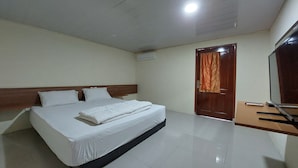 Una habitación de hotel con una cama grande, un cabecero de madera, un televisor de pantalla plana y una puerta de madera con cortina.