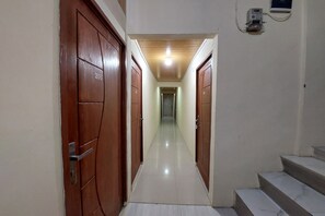 Un pasillo con puertas de madera, numeradas 205 y 208, que conduce a una escalera.