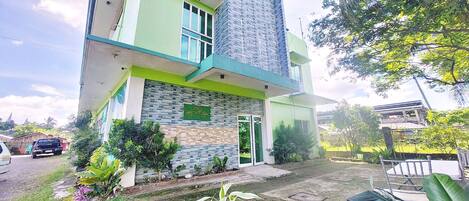 A multi-story building with a green and white facade, a stone accent wall, and a green door.