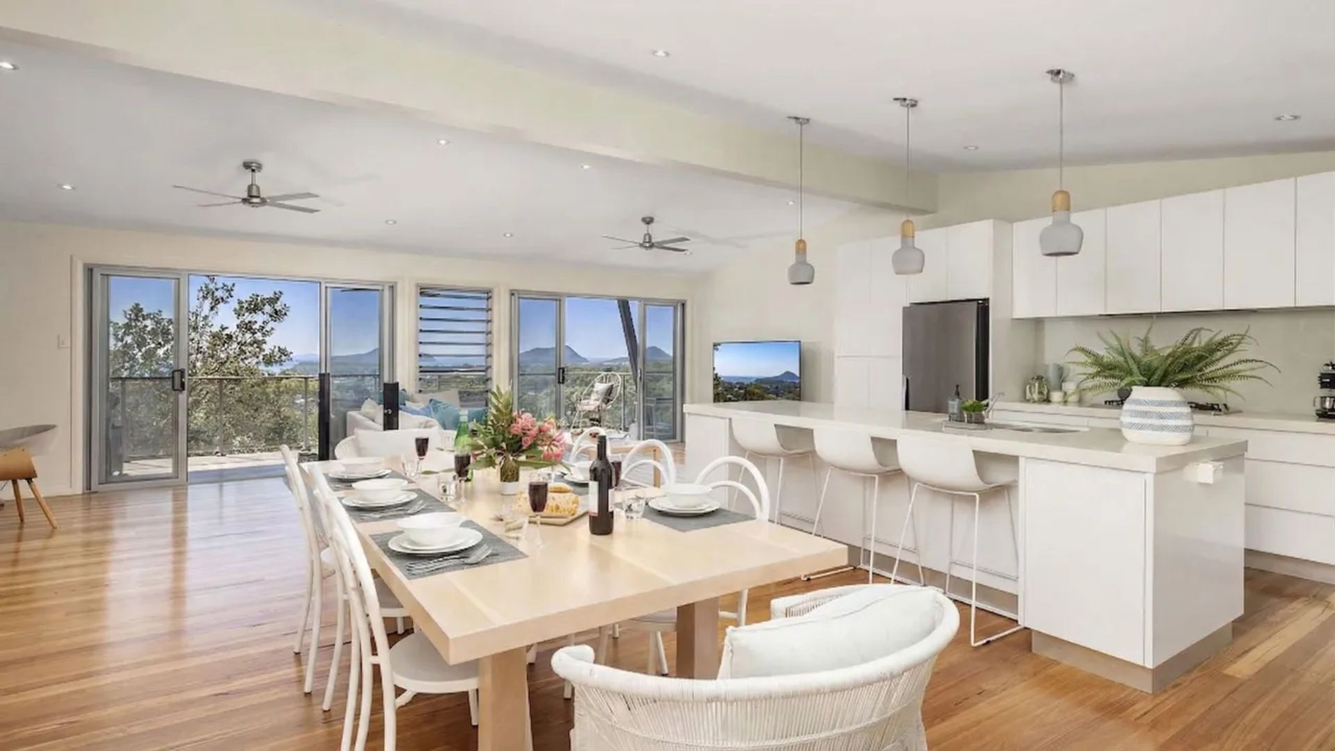 A modern kitchen with white cabinetry, a central island, and a dining area with a table set for four.