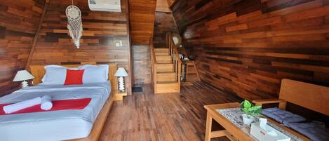 A wooden cabin-style room with a bed, bedside tables, a bench, and a staircase.