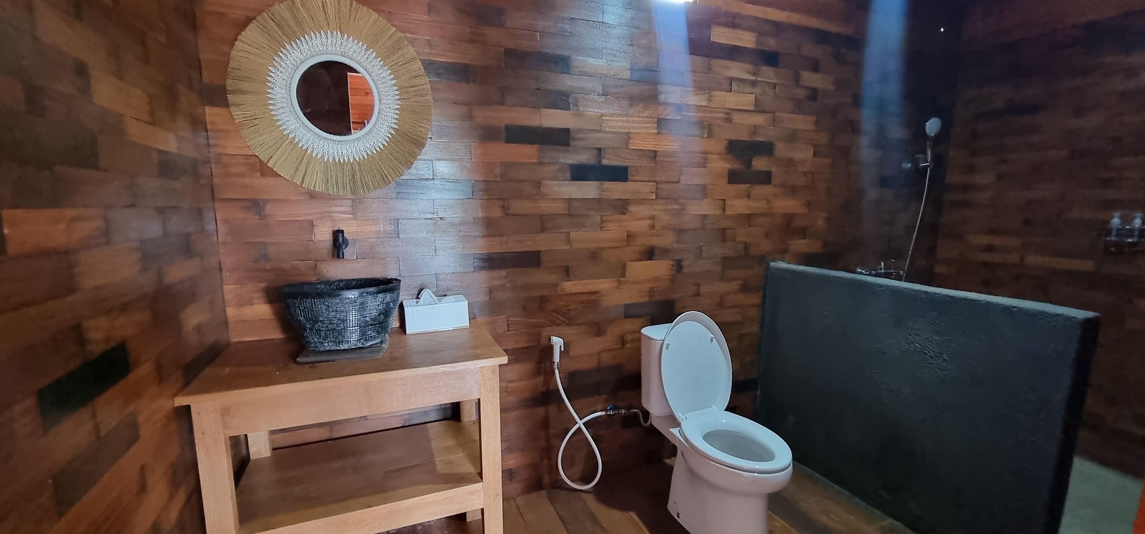 A wooden wall with a round mirror and a sink.