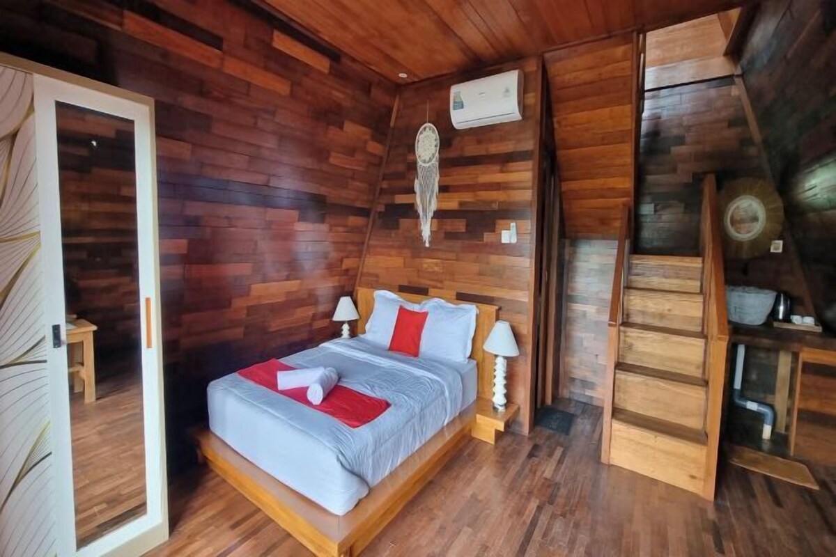 A wooden-paneled bedroom with a bed, bedside lamps, and a dreamcatcher on the wall.