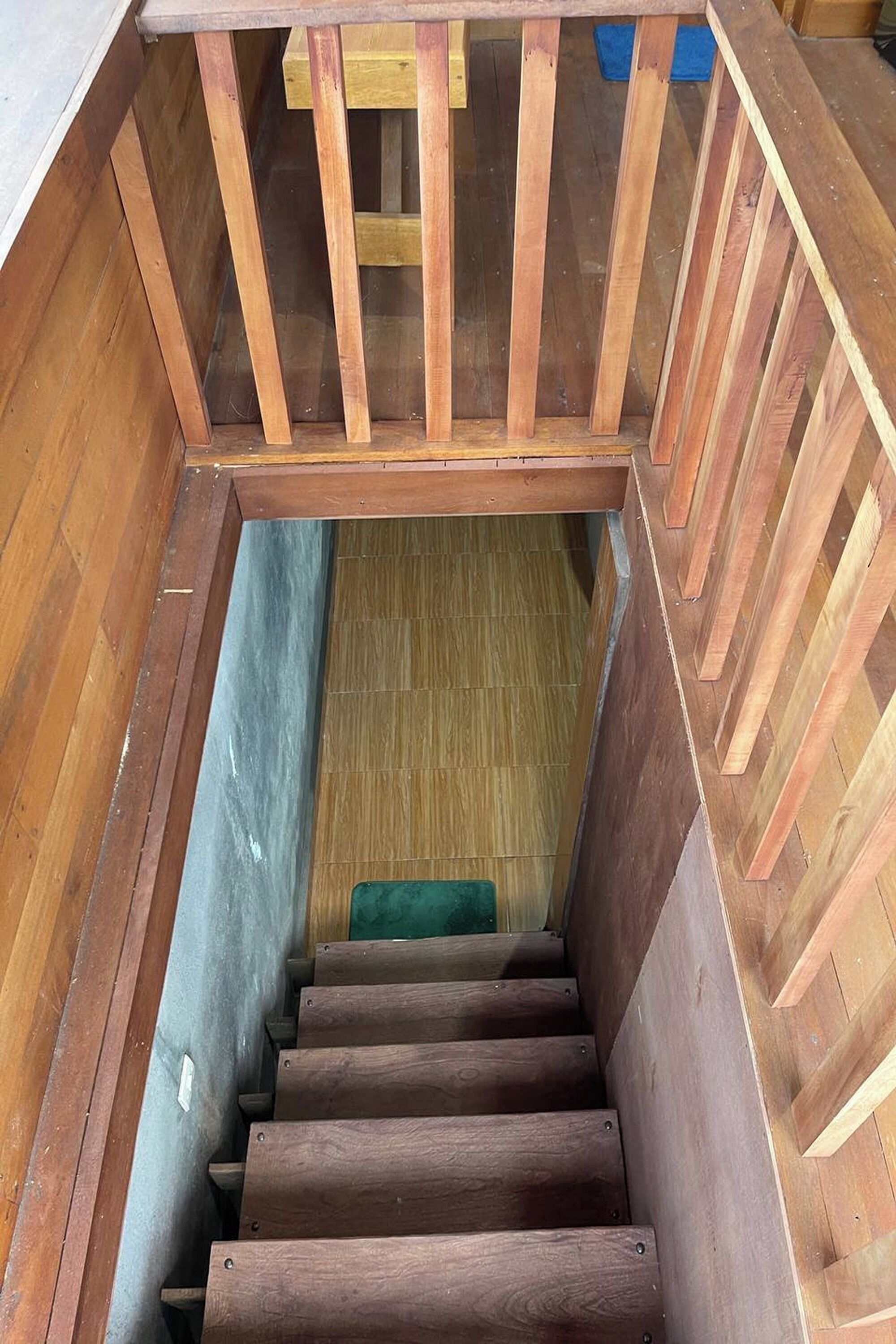 Un escalier en bois, doté d’une rampe, qui mène à un niveau inférieur.