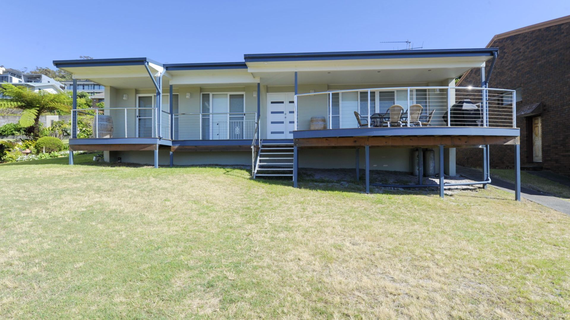 Ein modernes, zweistöckiges Haus mit Balkon und überdachter Terrasse.
