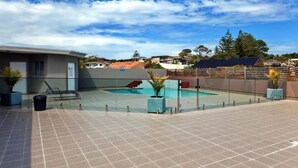 Ein Poolbereich auf dem Dach mit freiem Blick auf die umliegende Nachbarschaft, einschließlich Häuser und Bäume.