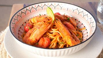 A bowl of pasta with shrimp and tomatoes, garnished with a lime wedge.