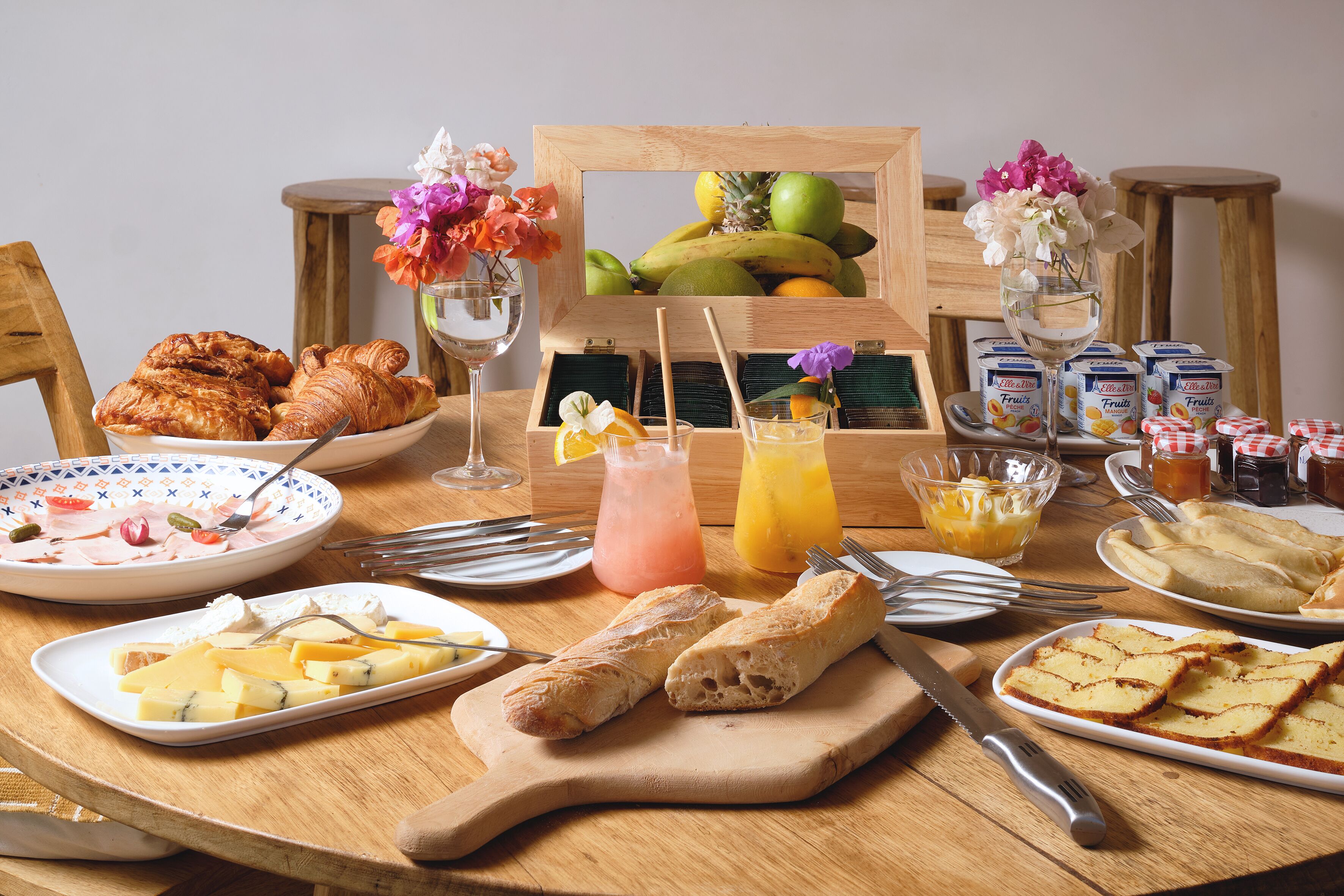Una mesa de desayuno con cruasanes, queso, pan y fruta.