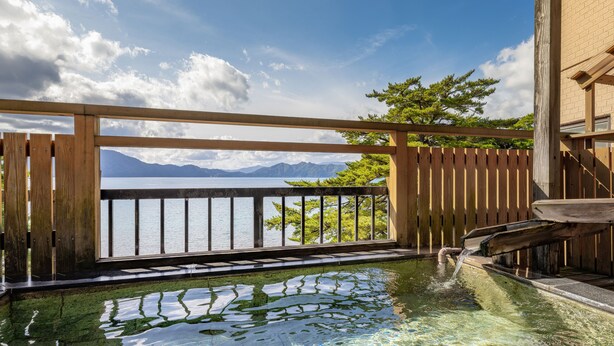 Una terraza de madera con vistas a un lago y montañas.