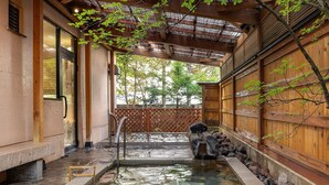 Un onsen japonés tradicional con un baño de piedra, paredes de madera y un tejado de paja.
