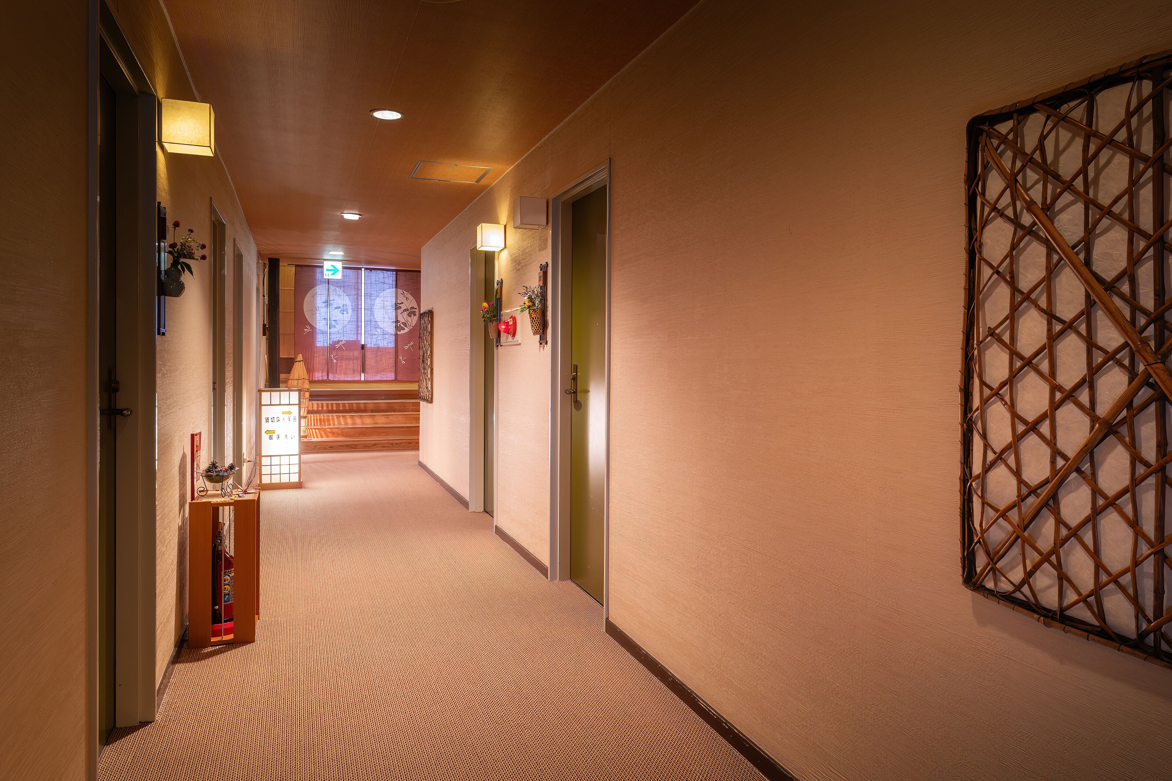 A hallway with carpeted floors, wooden doors, and a decorative wall panel.