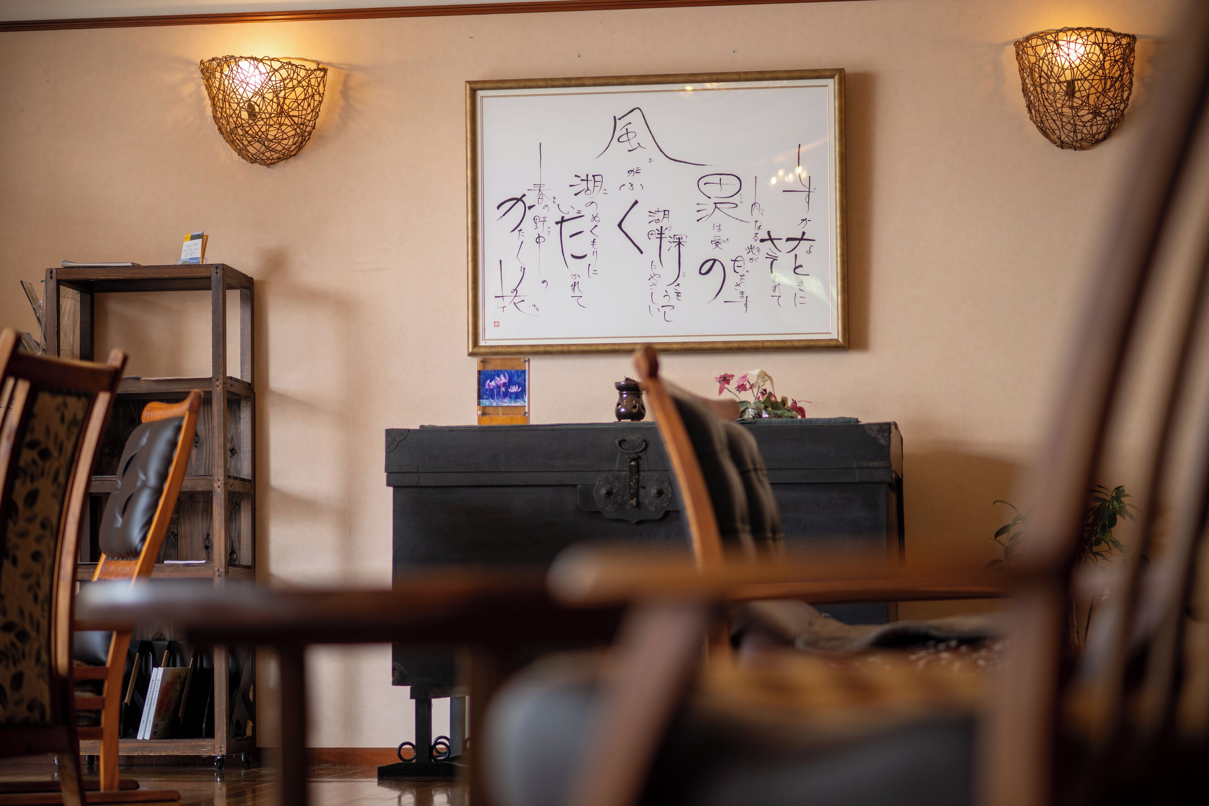 A room with a framed artwork on the wall, a wooden cabinet, and a chair.