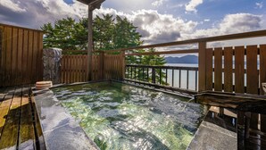 Una terraza de madera con un jacuzzi, una valla de madera y vistas a las montañas.