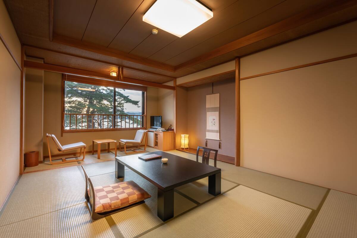 A traditional Japanese room with tatami flooring, a low table, and seating.