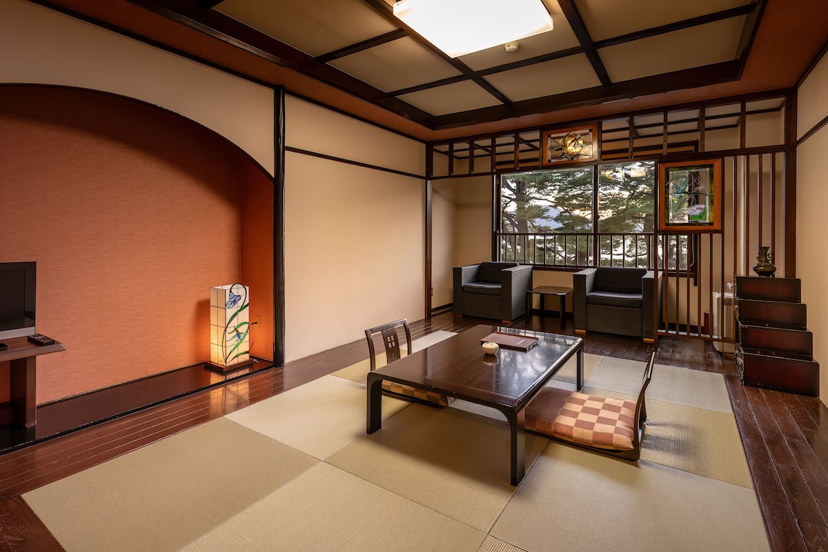 A traditional Japanese-style room with tatami flooring, a low table, and seating.