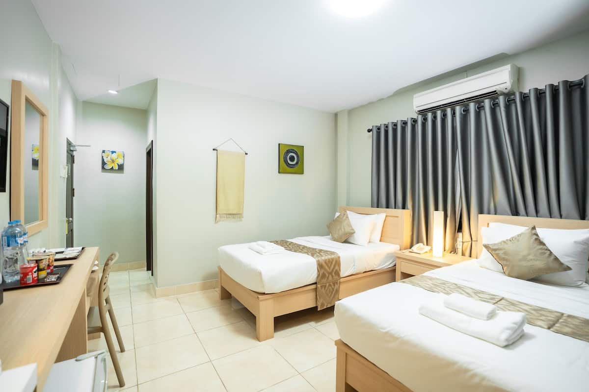 A hotel room with two beds, a desk, and a bathroom.