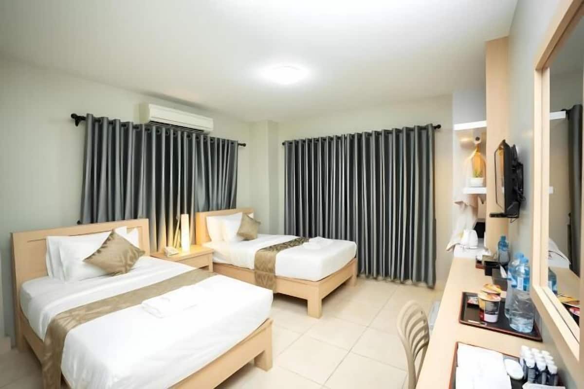A hotel room with two beds, a desk with toiletries, and a large mirror.