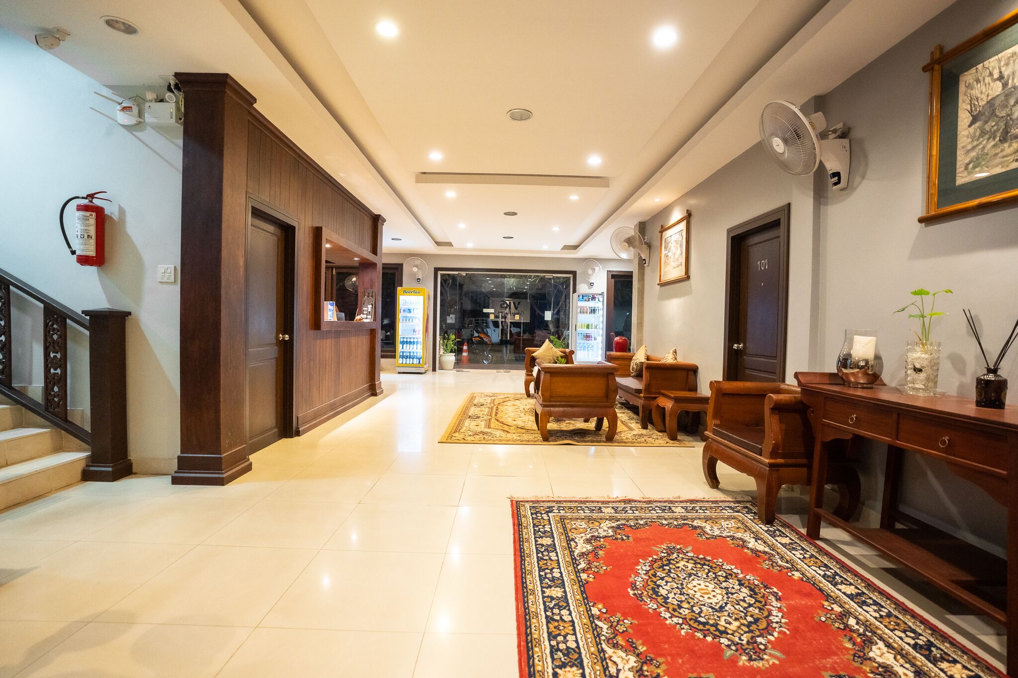 A hotel lobby with a reception desk, seating area, and a staircase.