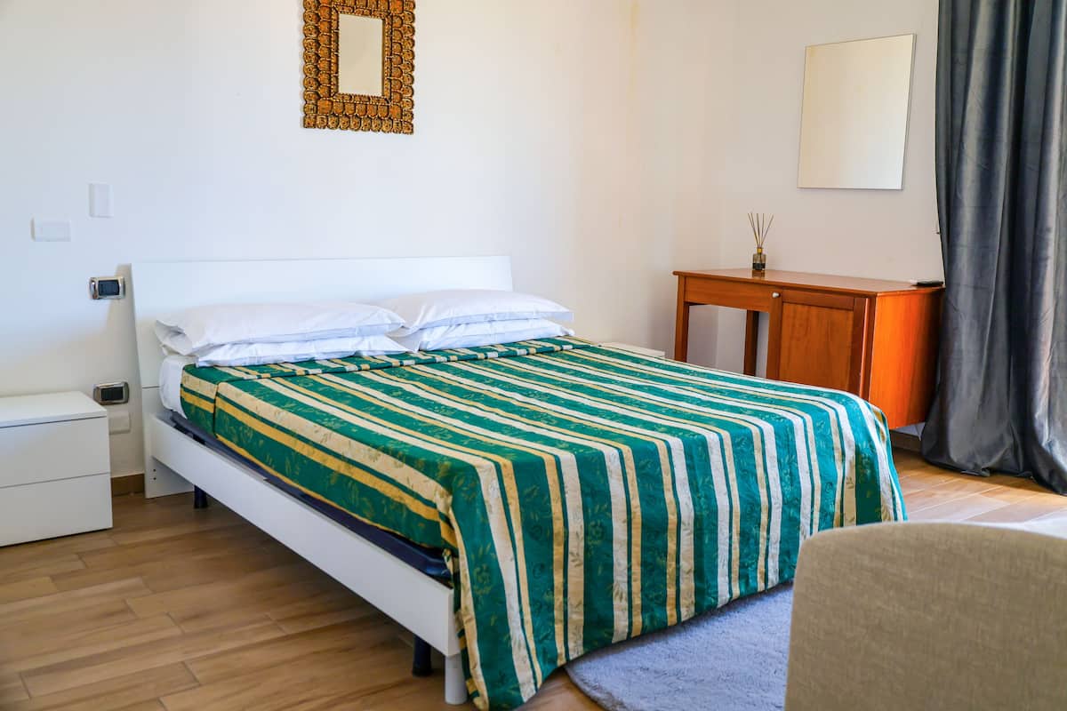 A neatly arranged bedroom with a bed, bedside table, and a small wooden side table.